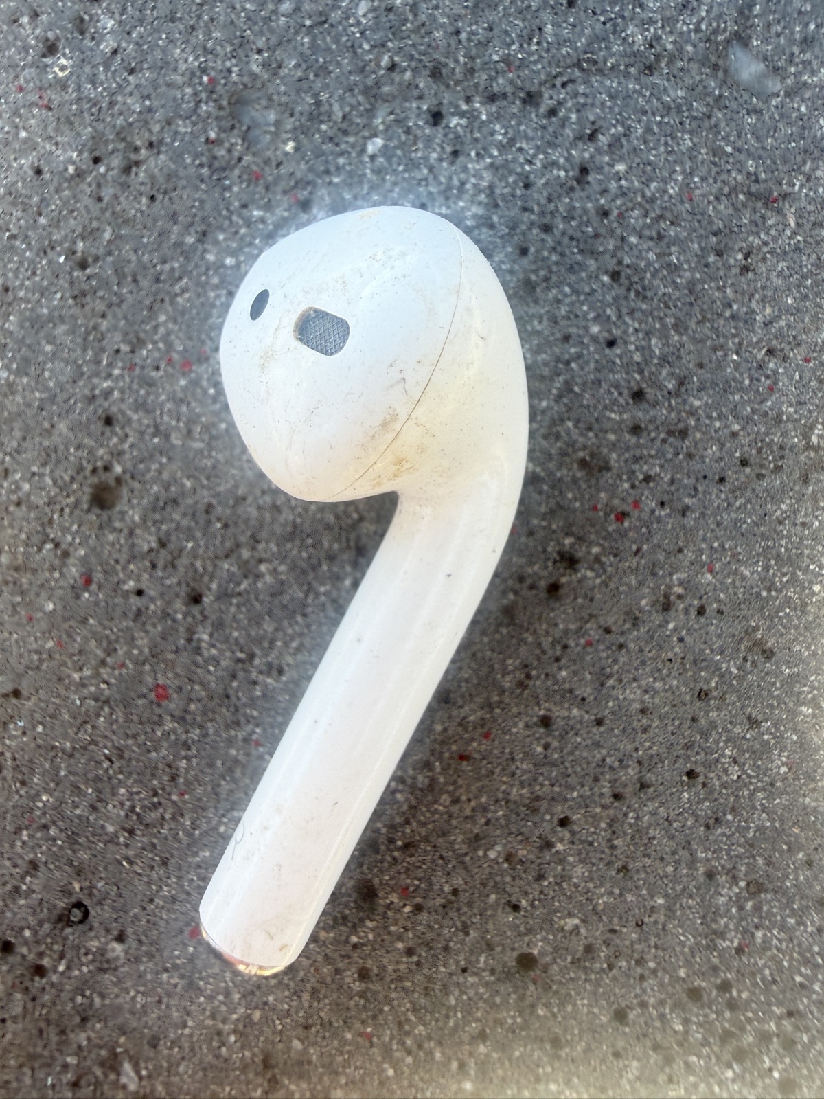 Close-up of the found right AirPod on concrete